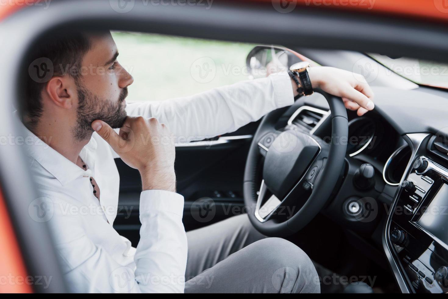 jeune homme d'affaires confiant assis au volant de sa nouvelle voiture photo