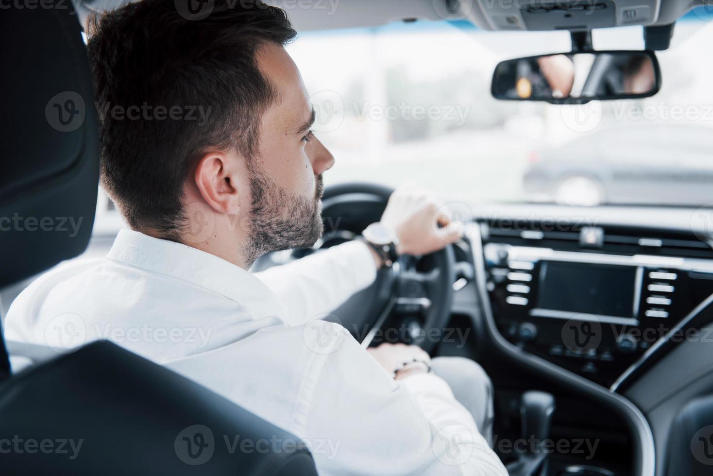 jeune homme d'affaires confiant assis au volant de sa nouvelle voiture photo