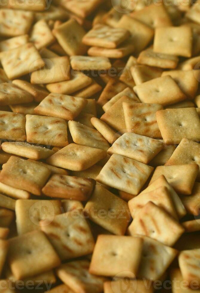 beaucoup de petits biscuits sont de forme carrée. un motif d'un craquelin de sel jaune. image de fond avec de la pâte salée photo