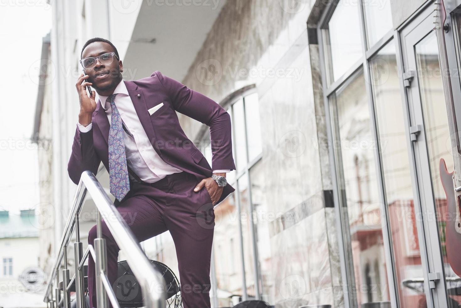 portrait d'un jeune et bel homme d'affaires afro-américain parlant en costume au téléphone. préparer une réunion d'affaires. photo