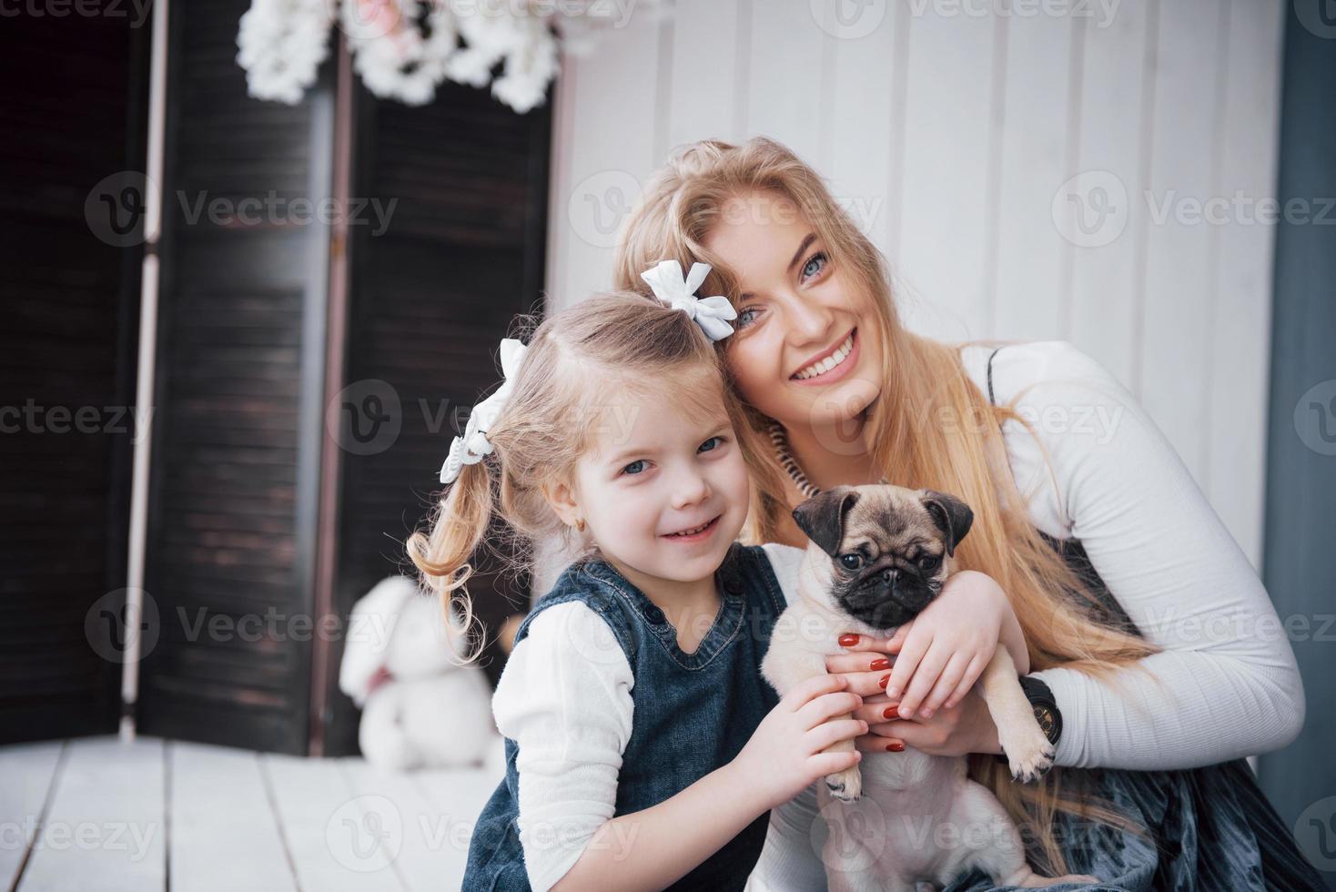 famille aimante heureuse. mère et sa fille enfant fille jouant et étreignant adorable carlin photo