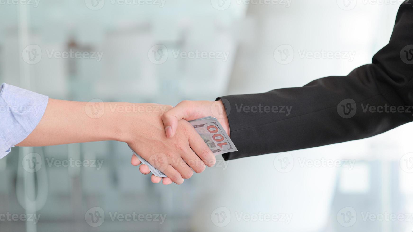 poignée de main et avoir de l'argent en main pour la corruption. photo