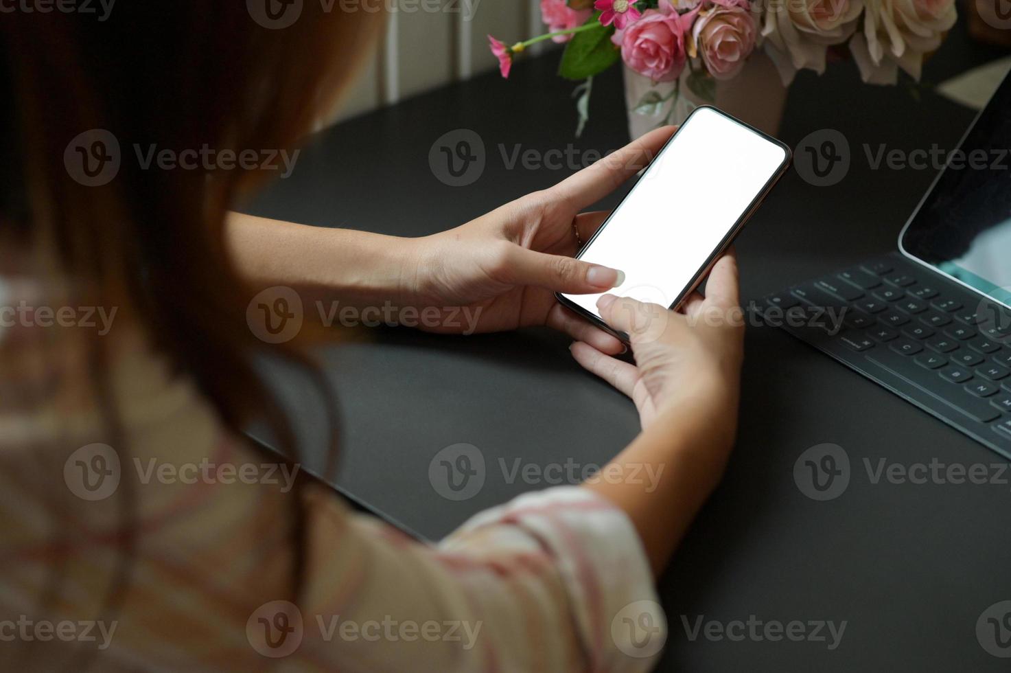 jeune femme utilisant un smartphone à la main pour rechercher des informations et un ordinateur portable sur le bureau du bureau. photo