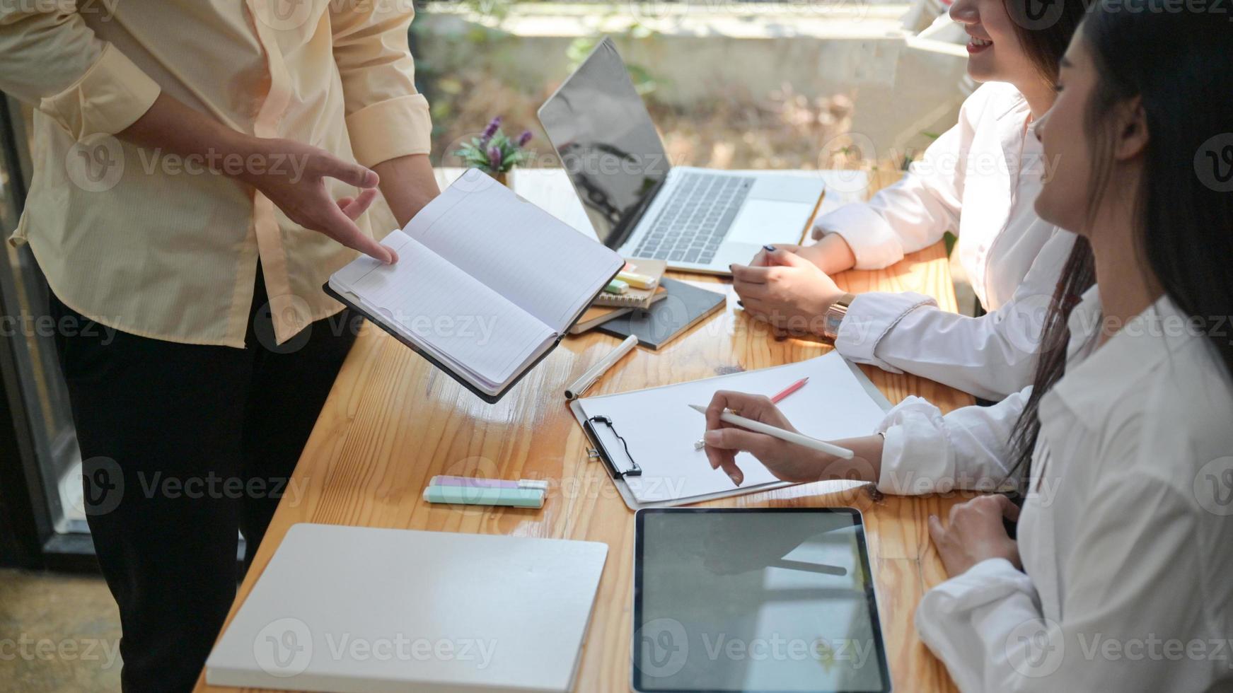 un groupe de jeunes professionnels recherche et fabrique des informations pour préparer de futurs projets. avec un ordinateur portable et un bloc-notes. photo