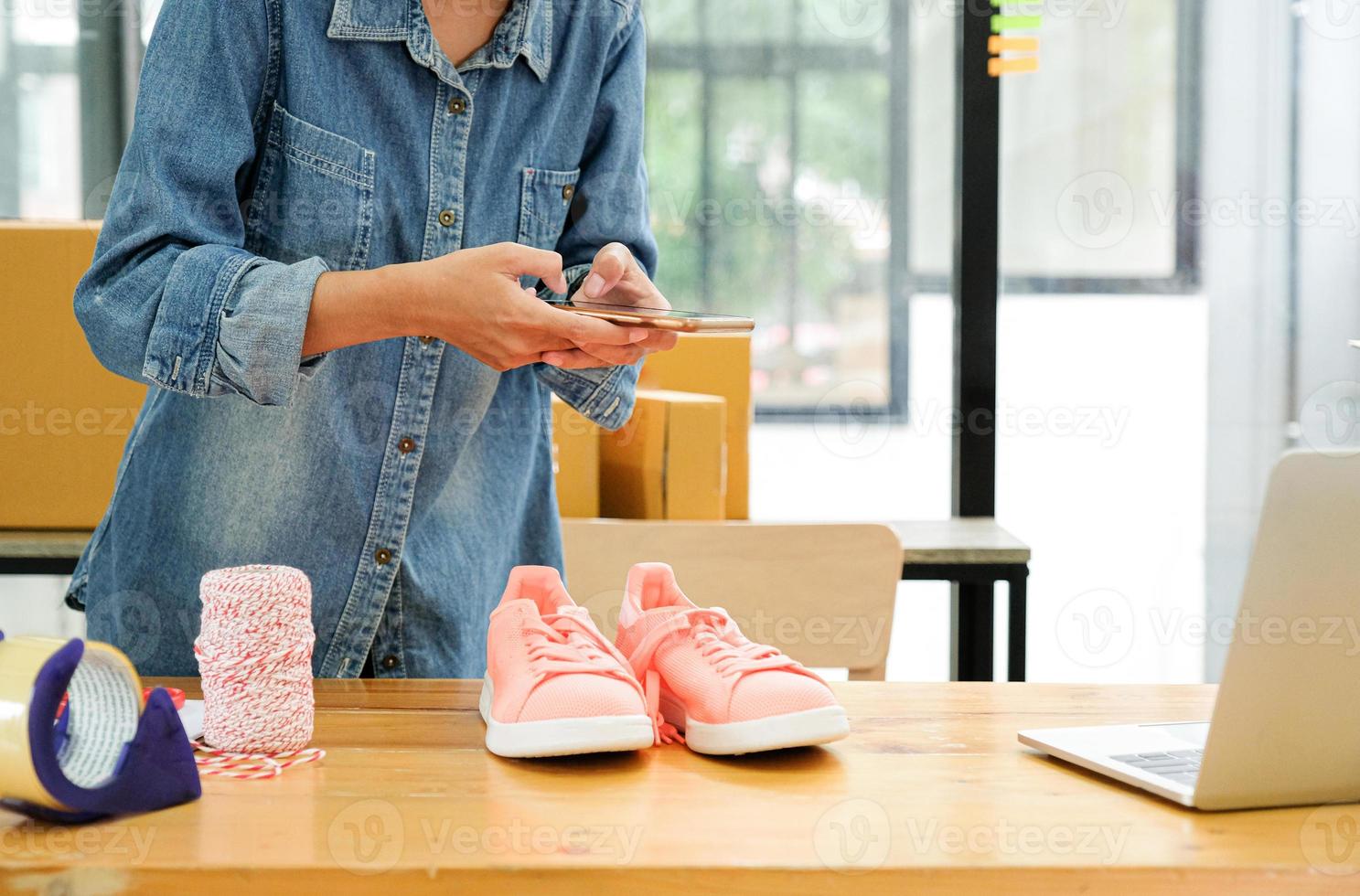 les vendeurs en ligne utilisent leur téléphone portable pour prendre des photos des chaussures envoyées aux clients.