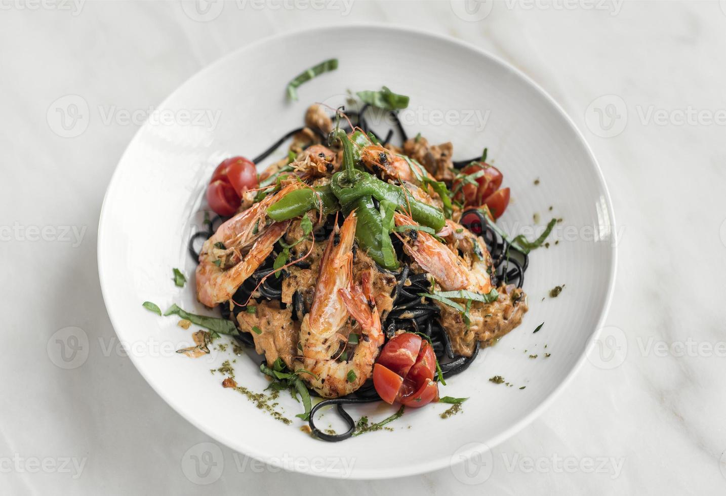 pâtes spaghetti à l'encre de seiche noire avec crevettes et légumes variés photo