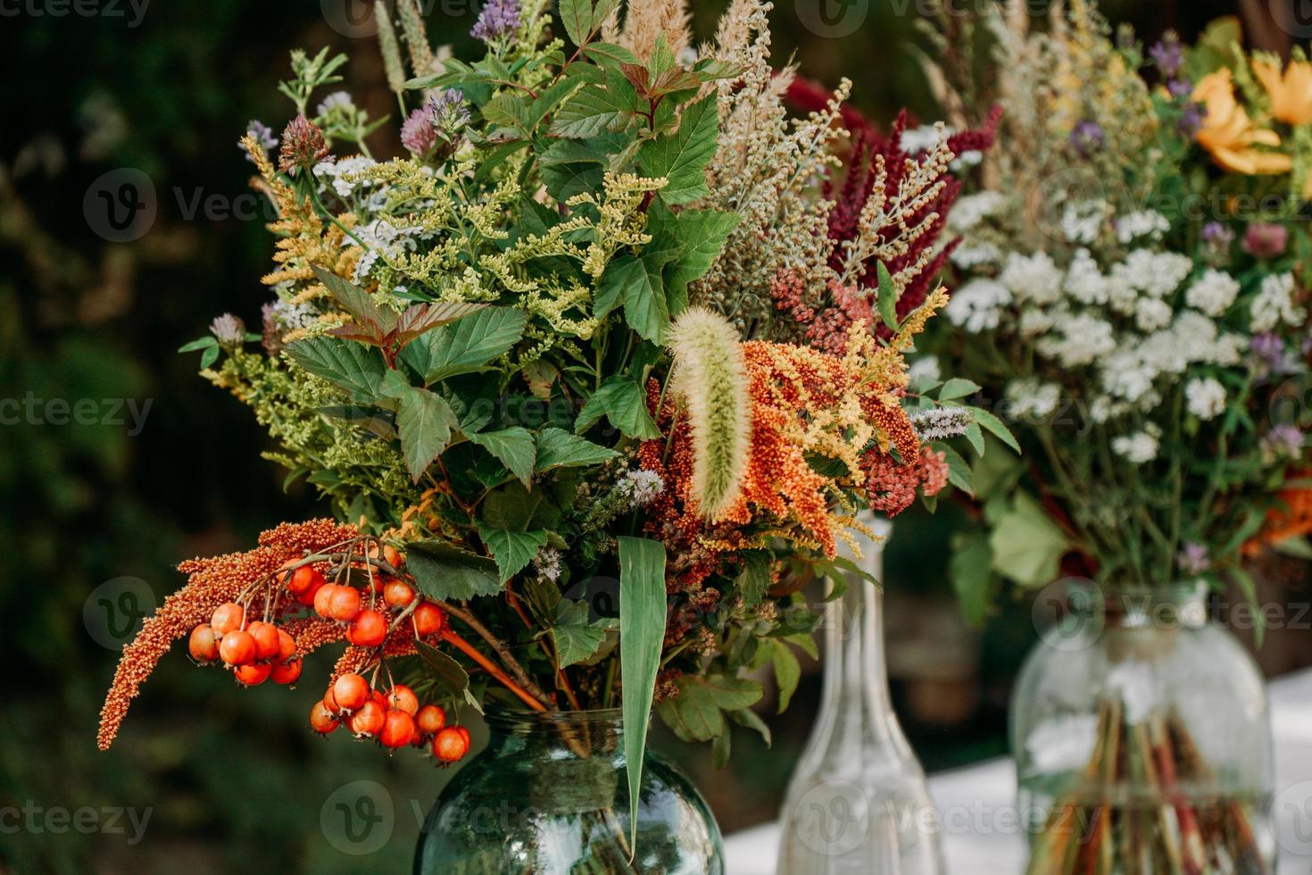 bouquets de style rustique sur la table dans des vases et bocaux en verre photo