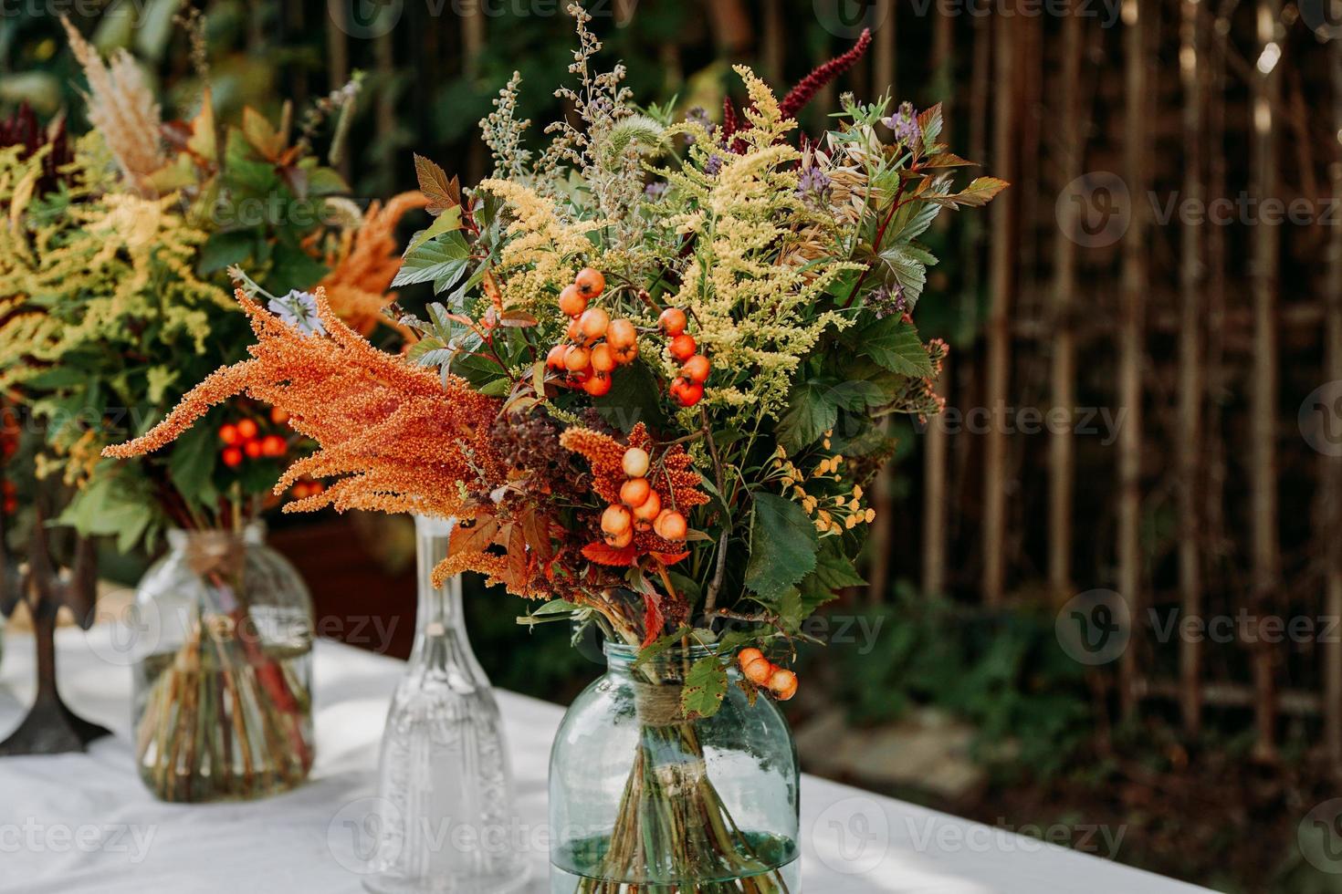 bouquets de style rustique sur la table dans des vases et bocaux en verre photo