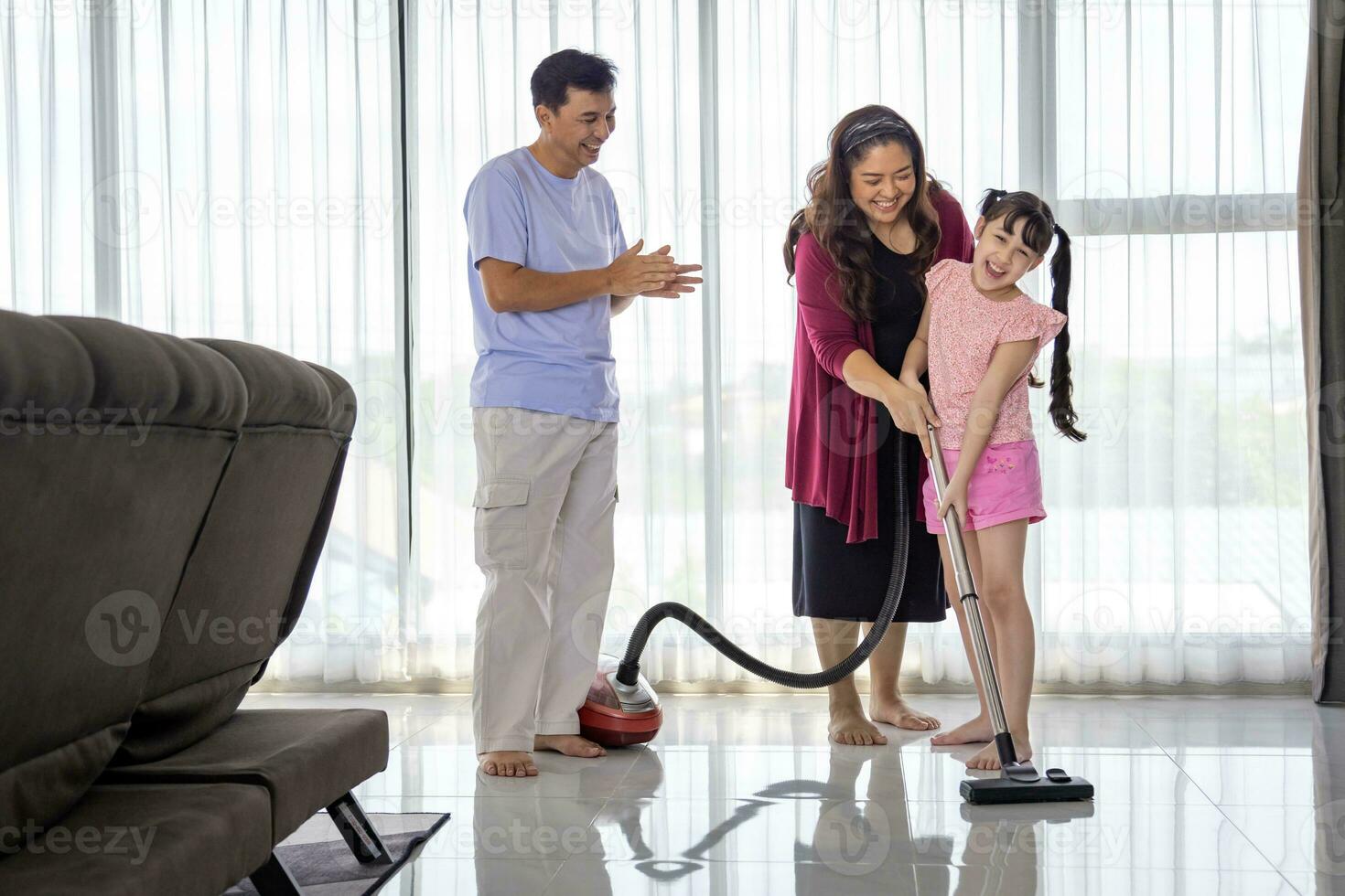 asiatique famille avec père, mère et fille Aidez-moi chaque autre à nettoyage maison en utilisant vide machine pour du quotidien routine corvées et Entretien ménager concept photo