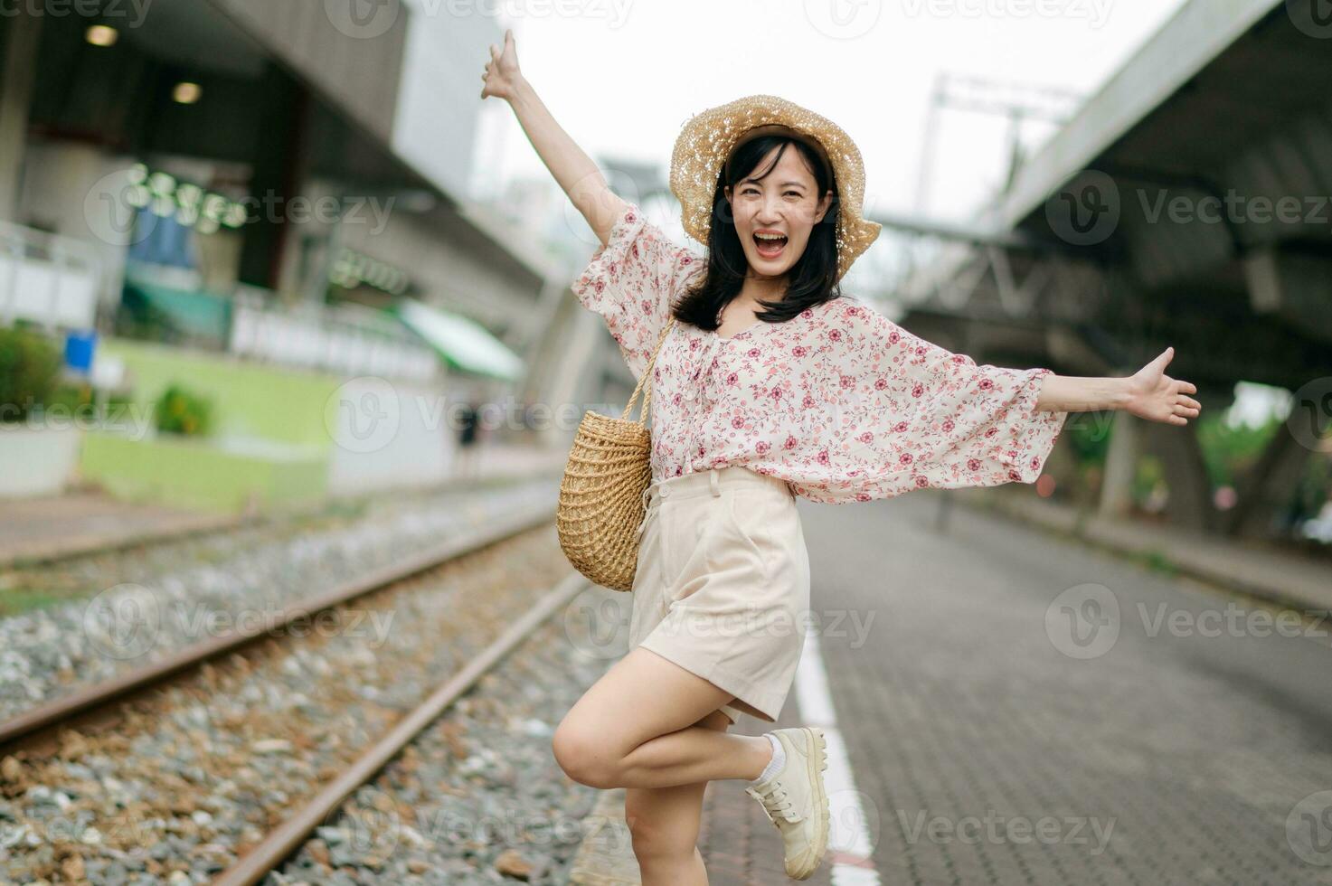 Jeune asiatique femme voyageur avec tissage panier content souriant à la recherche à une caméra à côté de train chemin de fer. périple voyage mode de vie, monde Voyage explorateur ou Asie été tourisme concept. photo