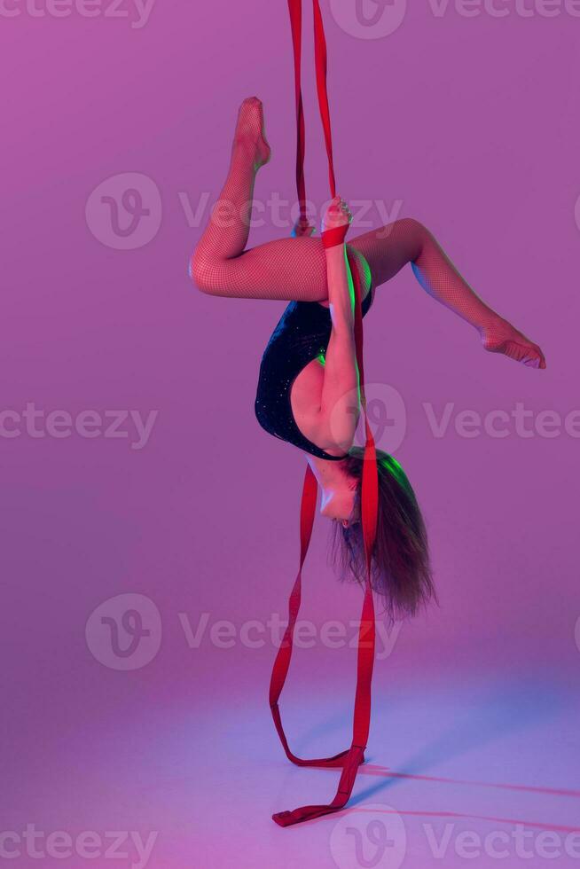 magnifique fille dans une noir maillot de bain est performant un acrobatique éléments dans studio. photo