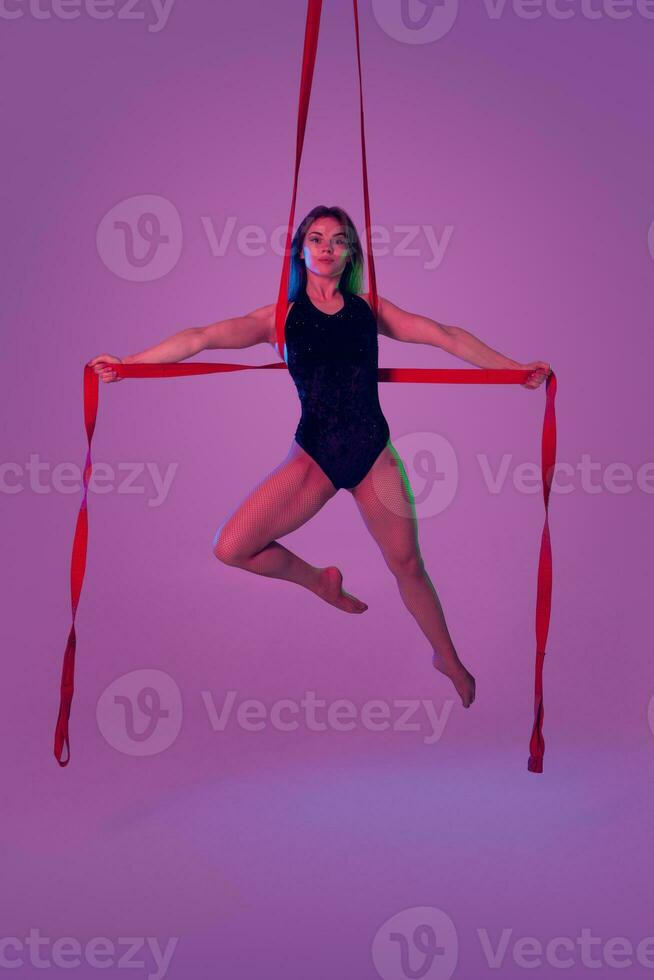 magnifique fille dans une noir maillot de bain est performant un acrobatique éléments dans studio. photo