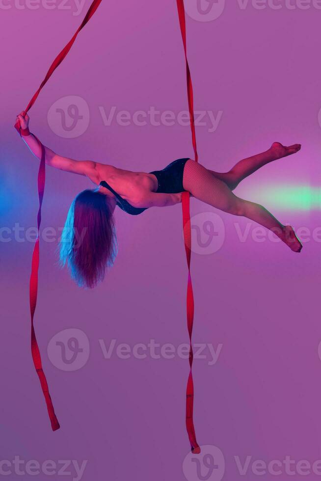 magnifique fille dans une noir maillot de bain est performant un acrobatique éléments dans studio. photo