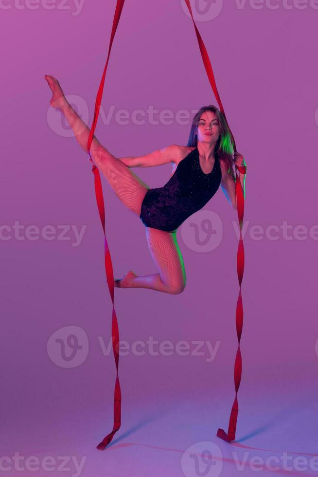 magnifique fille dans une noir maillot de bain est performant un acrobatique éléments dans studio. photo