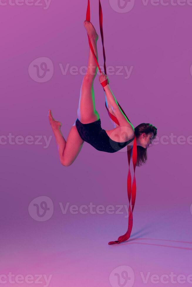 magnifique fille dans une noir maillot de bain est performant un acrobatique éléments dans studio. photo