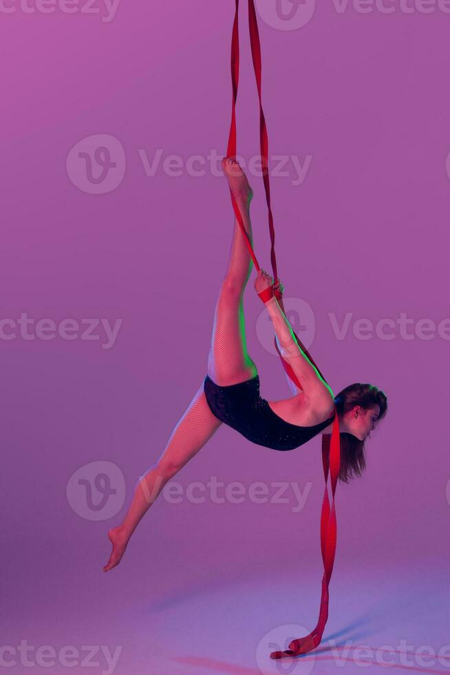 magnifique fille dans une noir maillot de bain est performant un acrobatique éléments dans studio. photo