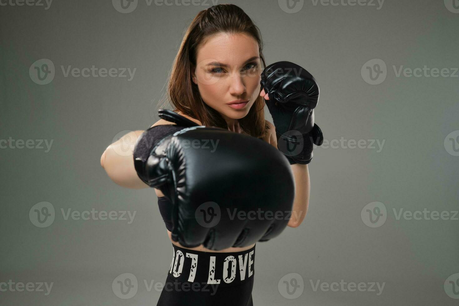 athlétique femme dans boxe gants est pratiquant karaté dans studio. photo