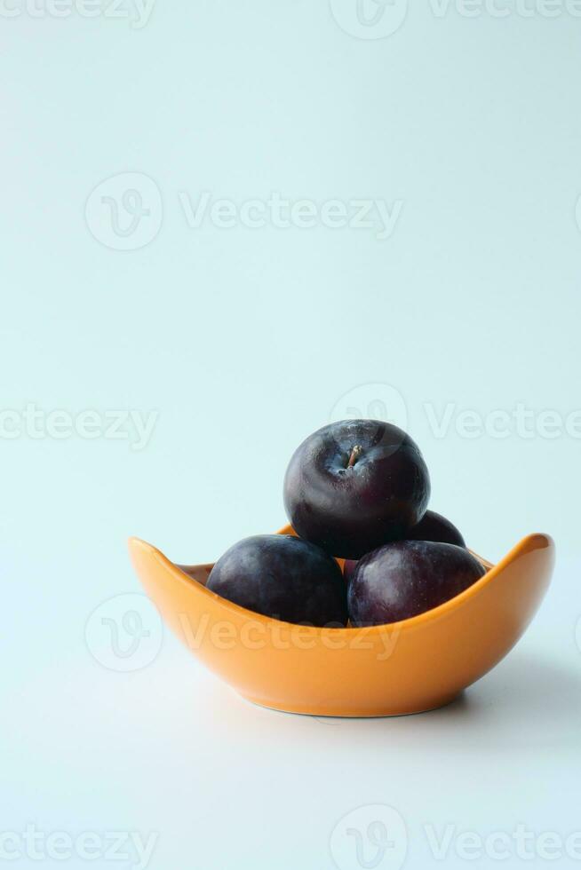 Frais prunes dans une bol sur table photo