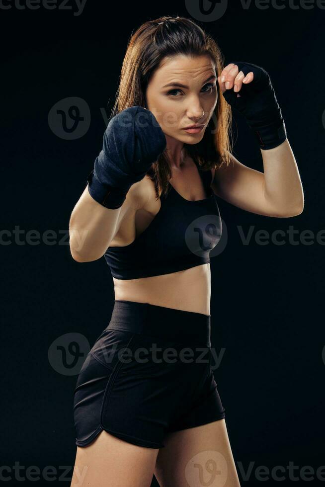athlétique femme dans boxe Mitaines est pratiquant karaté dans studio. photo
