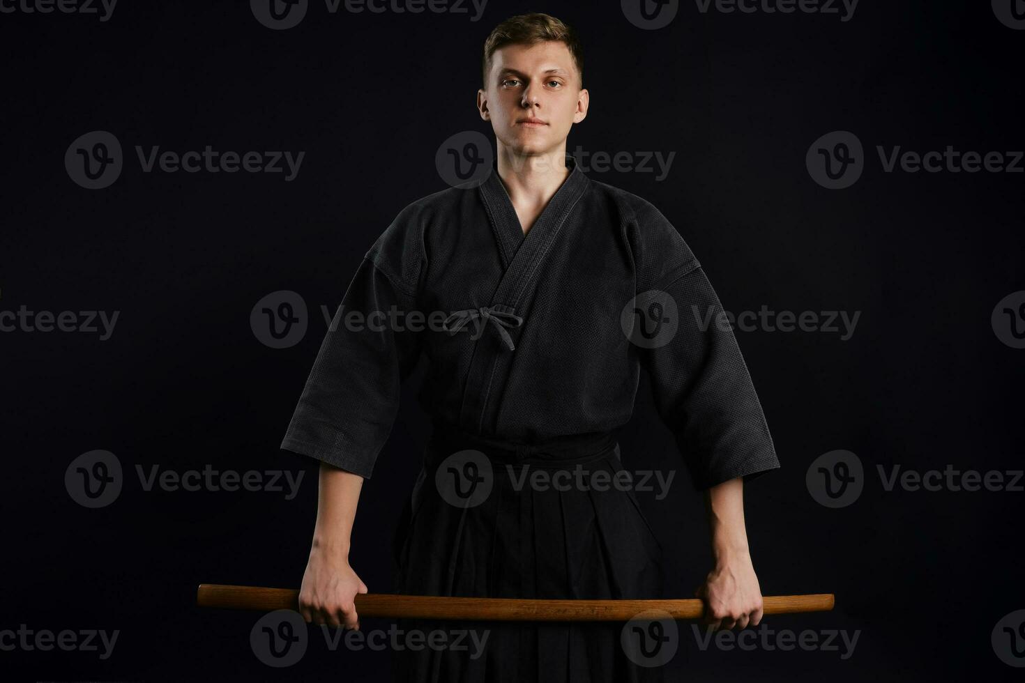 kendo gourou portant dans une traditionnel Japonais kimono est pratiquant martial art avec le shinaï bambou épée contre une noir studio Contexte. photo