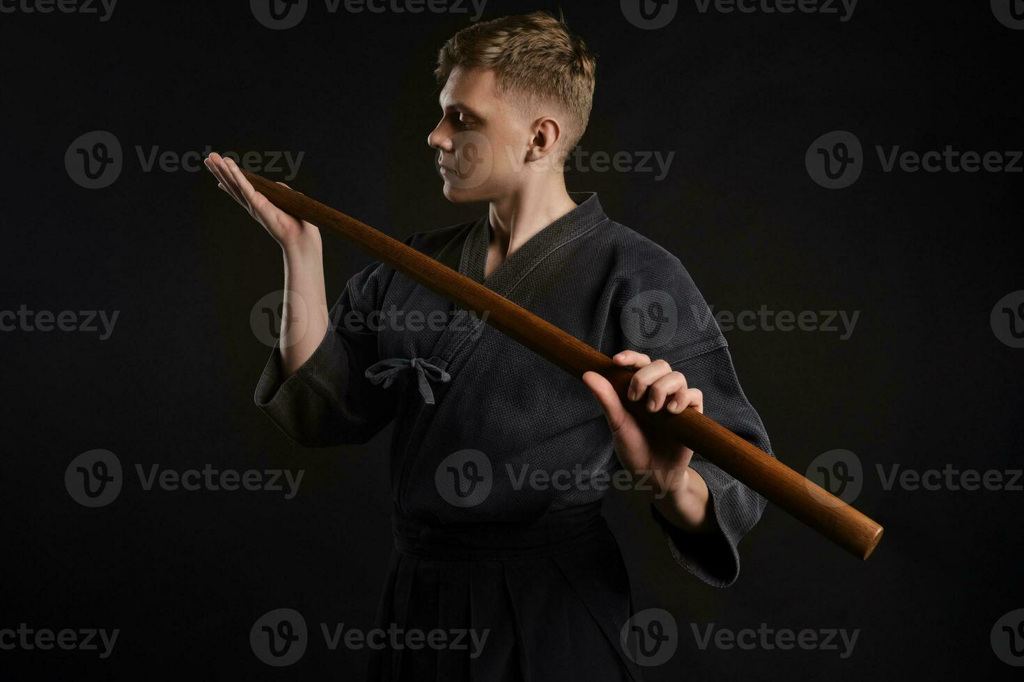 kendo gourou portant dans une traditionnel Japonais kimono est pratiquant martial art avec le shinaï bambou épée contre une noir studio Contexte. photo