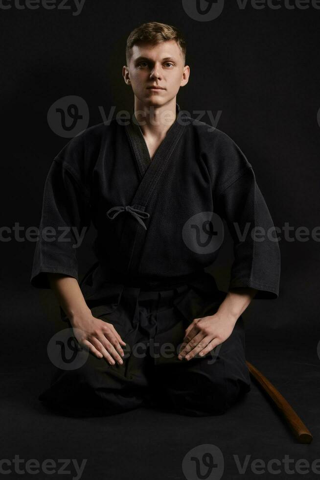 kendo gourou portant dans une traditionnel Japonais kimono est pratiquant martial art avec le shinaï bambou épée contre une noir studio Contexte. photo