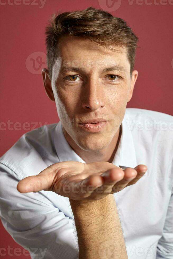 portrait de une Jeune brunet homme posant dans une studio contre une rouge Contexte. photo