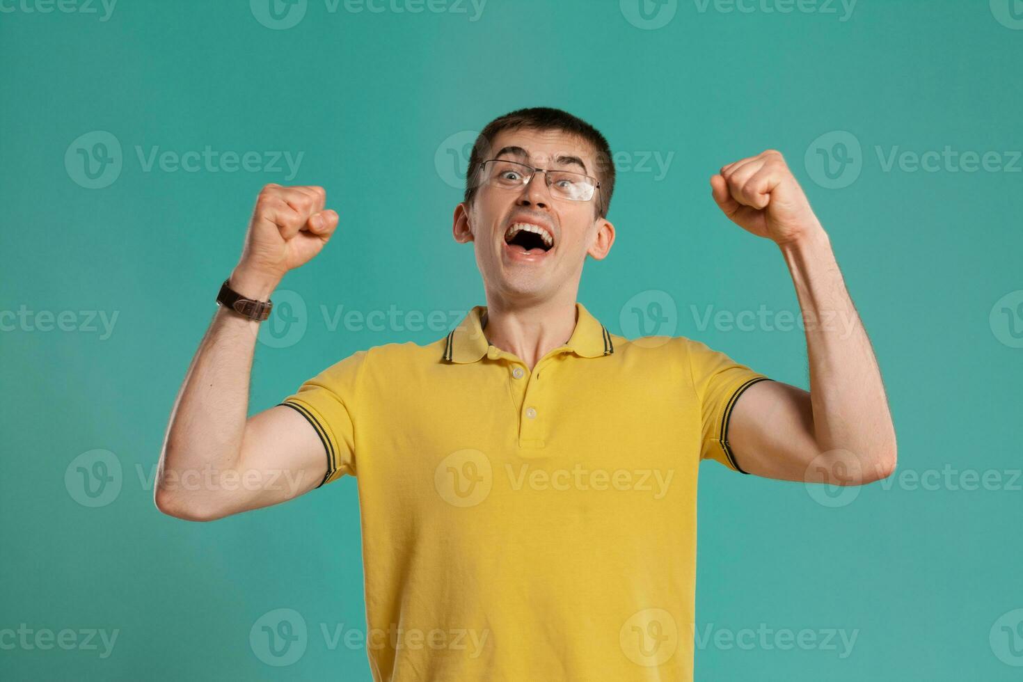 Beau gars dans une Jaune décontractée T-shirt est posant plus de une bleu Contexte. photo