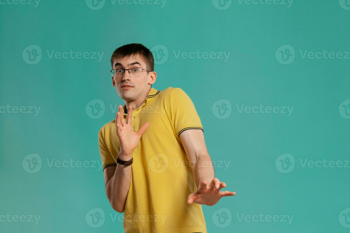 Beau gars dans une Jaune décontractée T-shirt est posant plus de une bleu Contexte. photo