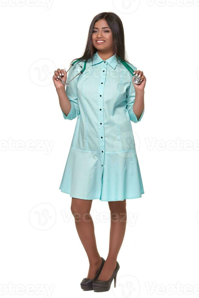 adorable Indien femelle médecin infirmière avec stéthoscope dans bleu vert robe isolé sur blanc Contexte photo