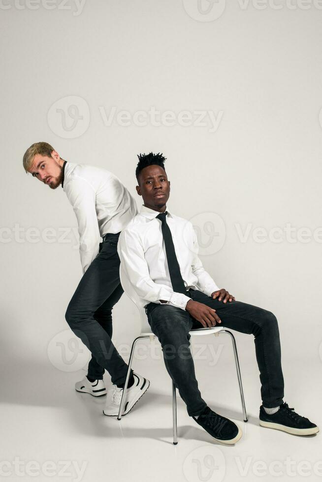 deux élégant Hommes posant et ayant amusement sur blanc Contexte. photo