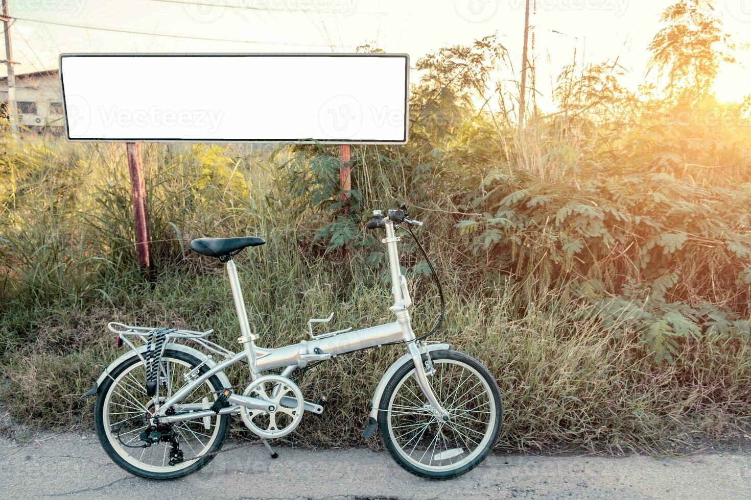 bicyclette pliant garé sur Prairie avec blanc affiche photo