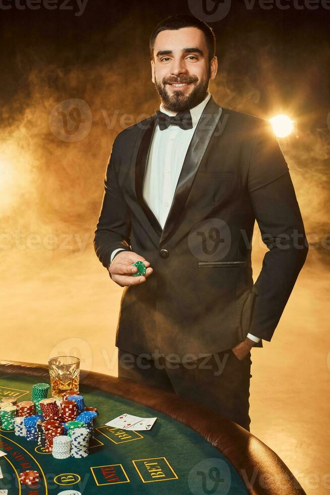 une Jeune homme dans une affaires costume permanent près poker tableau. homme des jeux de hasard. photo