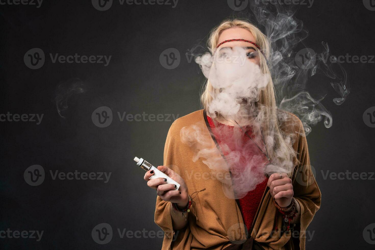 portrait de sexy Jeune branché fumeur vapoter fille. le femme est habillé dans le style de une bohème. vapeur concept. vapoter cigarette électronique. photo