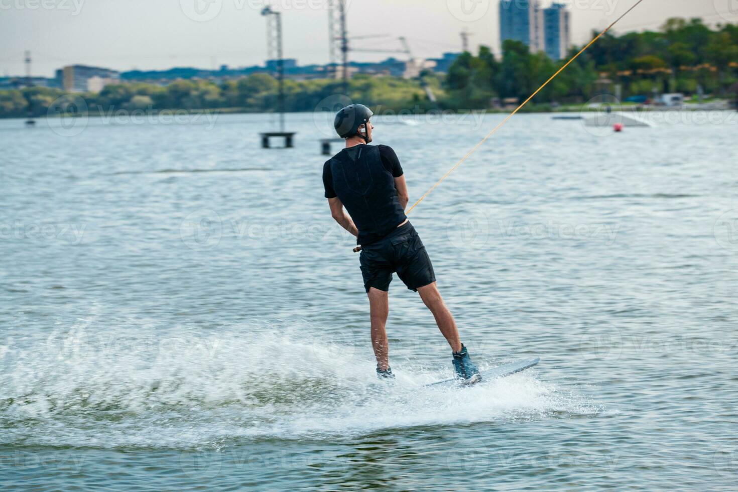 arrière vue de wakeboarder glissement sur l'eau de ville rivière en portant sur à remorquage corde photo