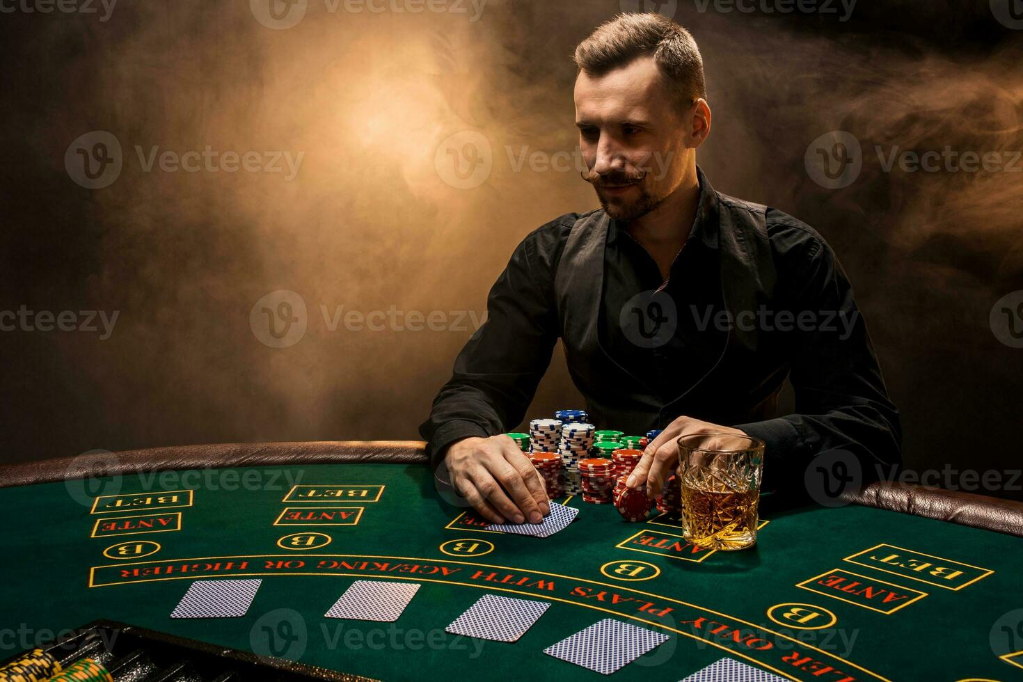 homme est en jouant poker avec une cigare et une whisky. une homme gagnant tout le frites sur le table avec épais cigarette fumée. photo
