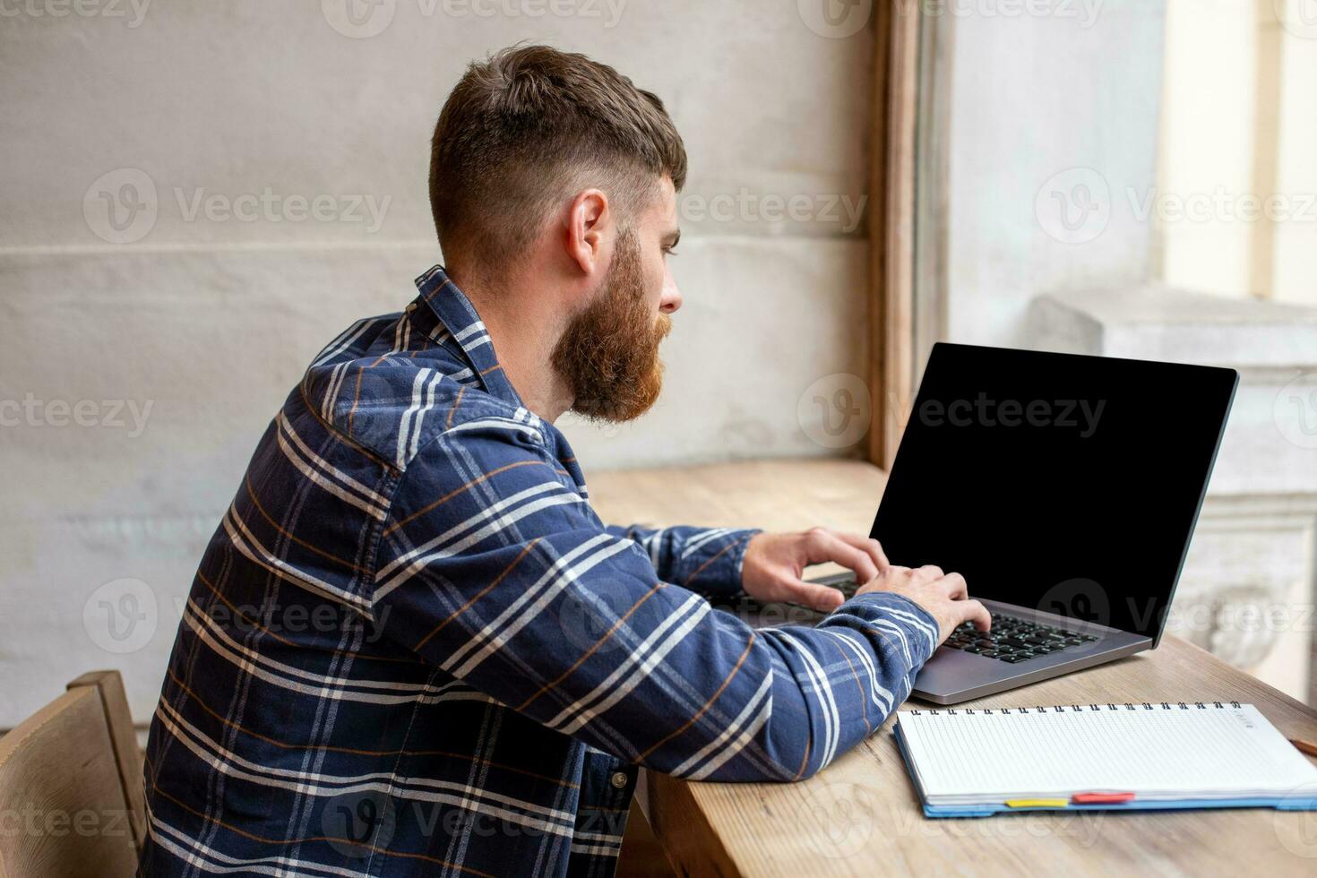 Jeune homme bavardage via net-book pendant travail Pause dans café boutique, Masculin séance dans de face ouvert portable ordinateur avec Vide copie espace filtrer. photo