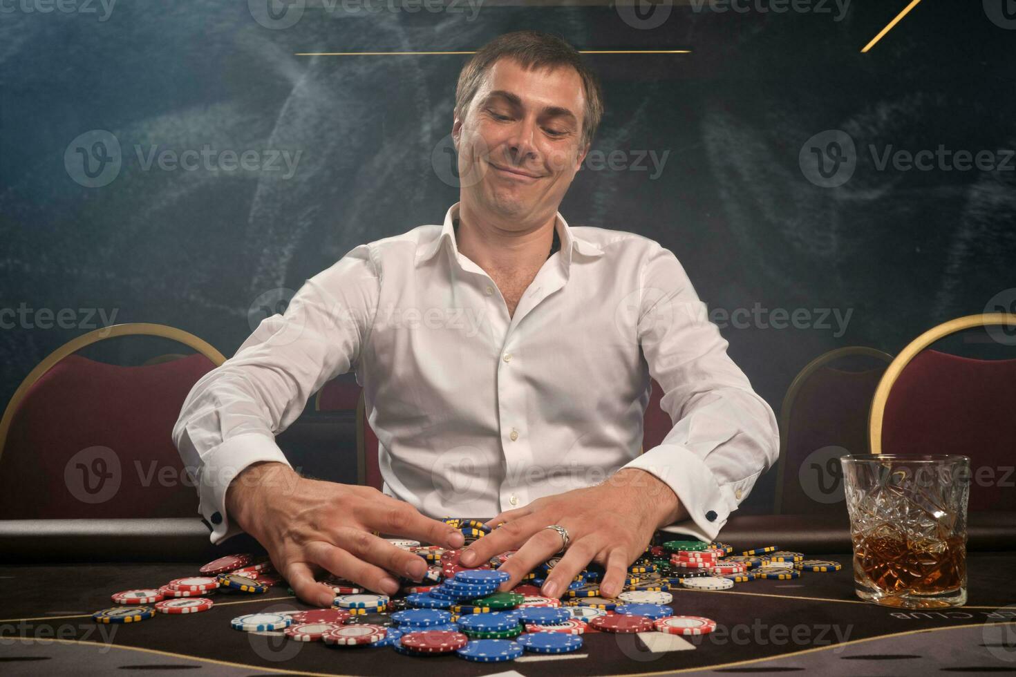 Beau émotif homme est en jouant poker séance à le table dans casino. photo