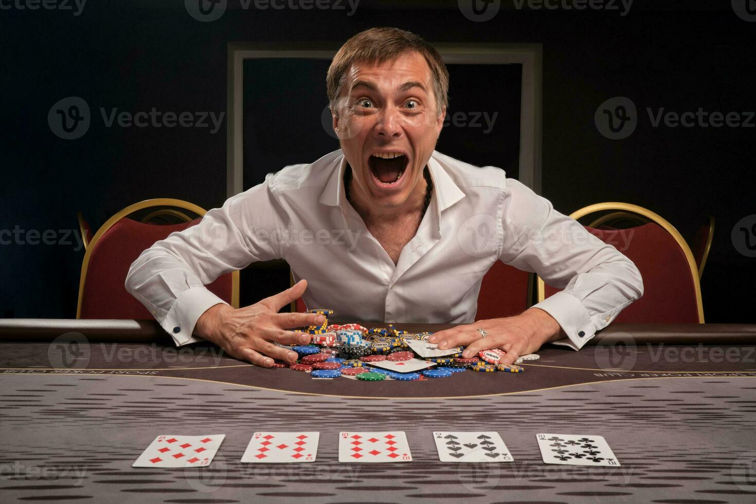 Beau émotif homme est en jouant poker séance à le table dans casino. photo