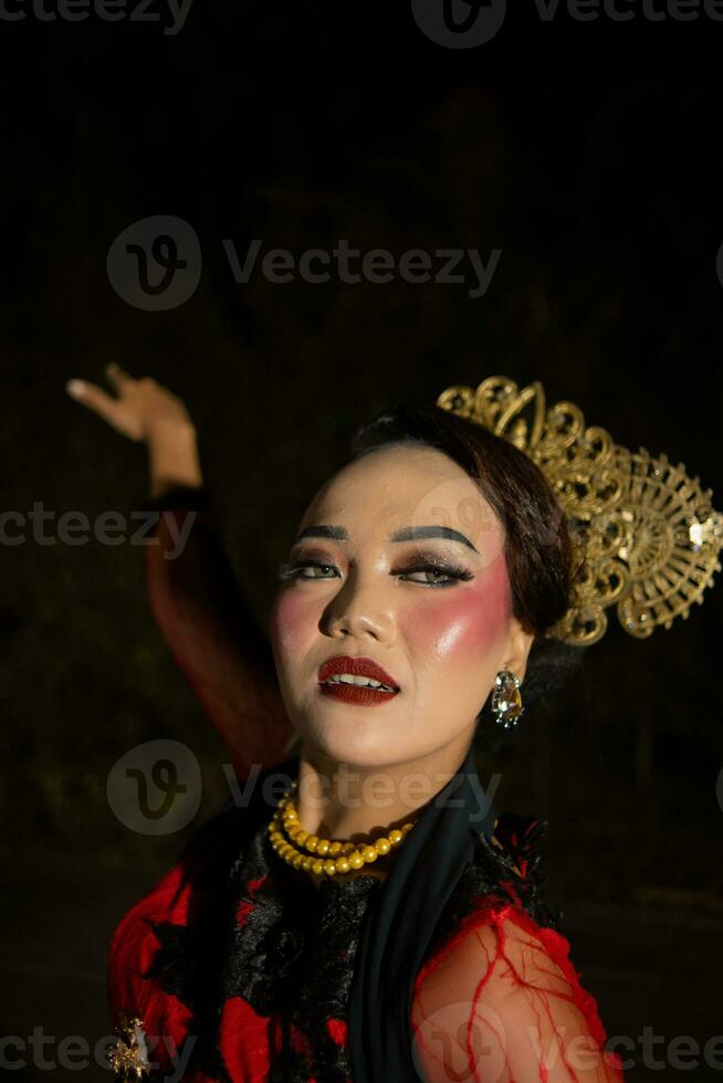 un asiatique femme avec maquillage sur sa visage et portant une noir châle tandis que dansant photo