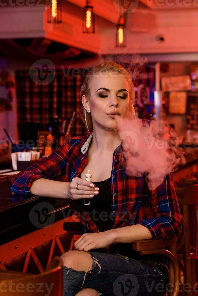 Jeune jolie femme fumée un électronique cigarette à le vape bar photo