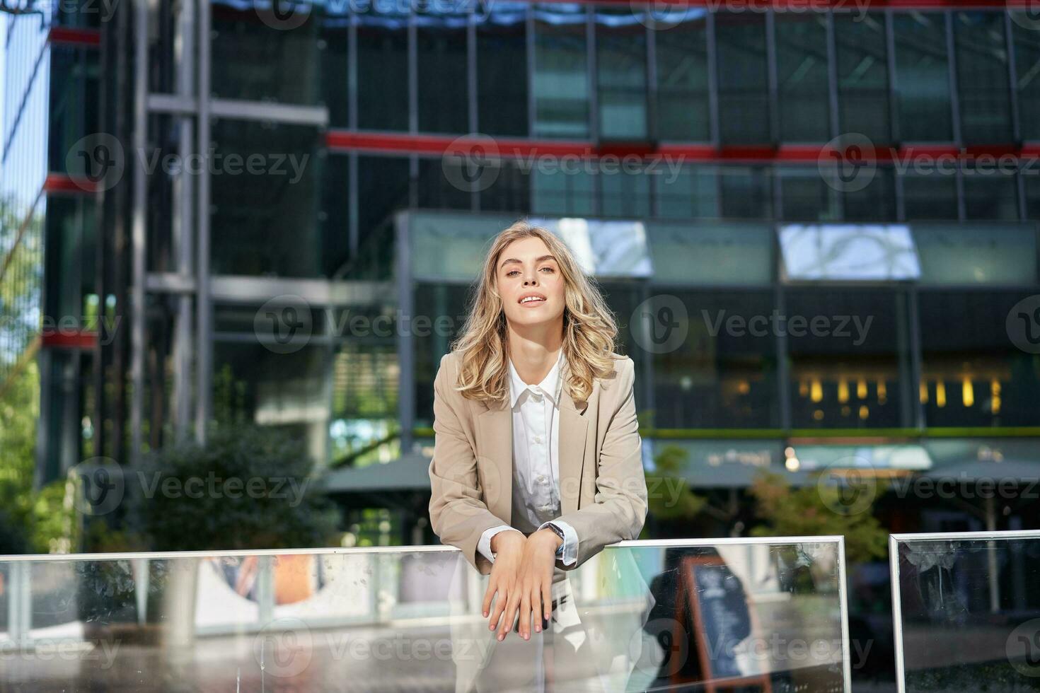 Jeune magnifique femme d'affaires permanent dans beige costume sur ensoleillé rue près Bureau bâtiments photo