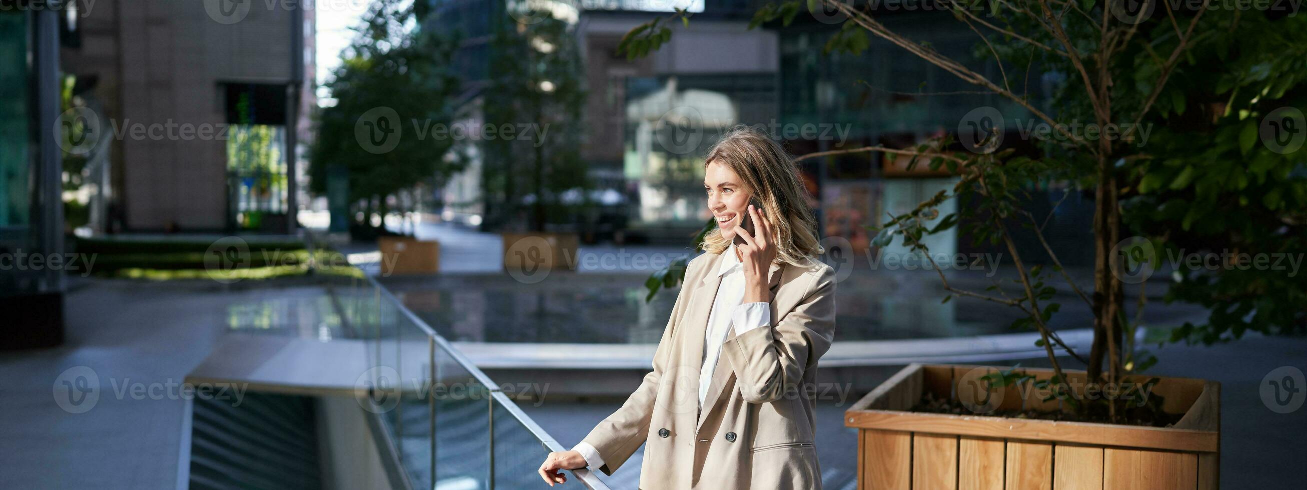 magnifique Jeune femme d'affaires dans costume pourparlers sur mobile téléphone sur rue. entreprise femme appels Quelqu'un sur téléphone tandis que des stands à l'extérieur photo