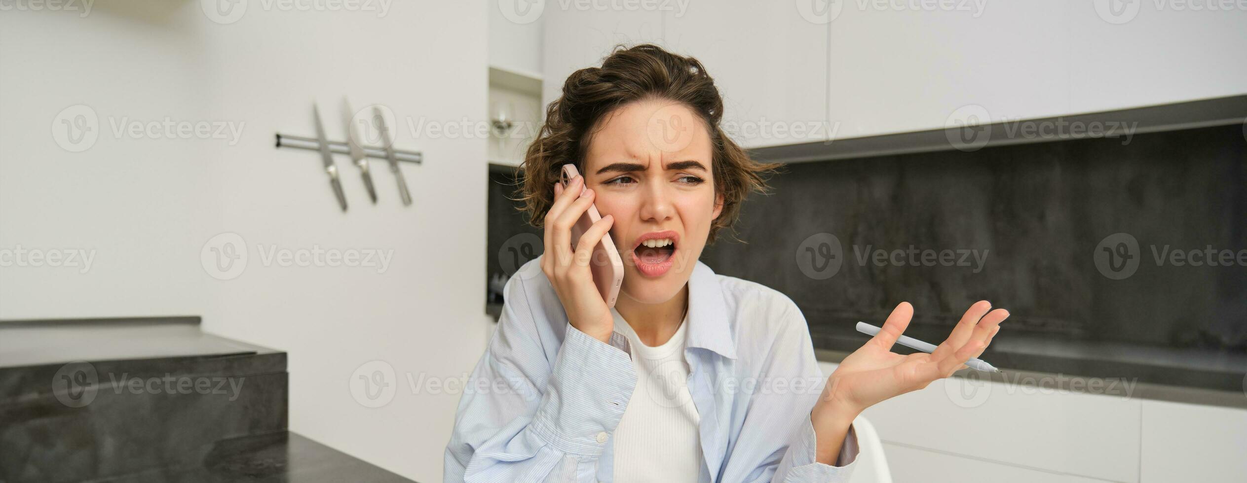 portrait de femme argumenter pendant téléphone appel, se plaindre à Quelqu'un plus de le Téléphone, séance à Accueil et en criant à téléphone intelligent photo