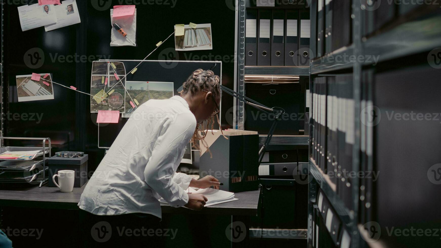 femme détective découvrir des indices sur preuve conseil, travail sur la criminalité résolution dans archiver chambre. femelle enquêteur examiner surveillance images, recherche pour perspicacité et détails. photo