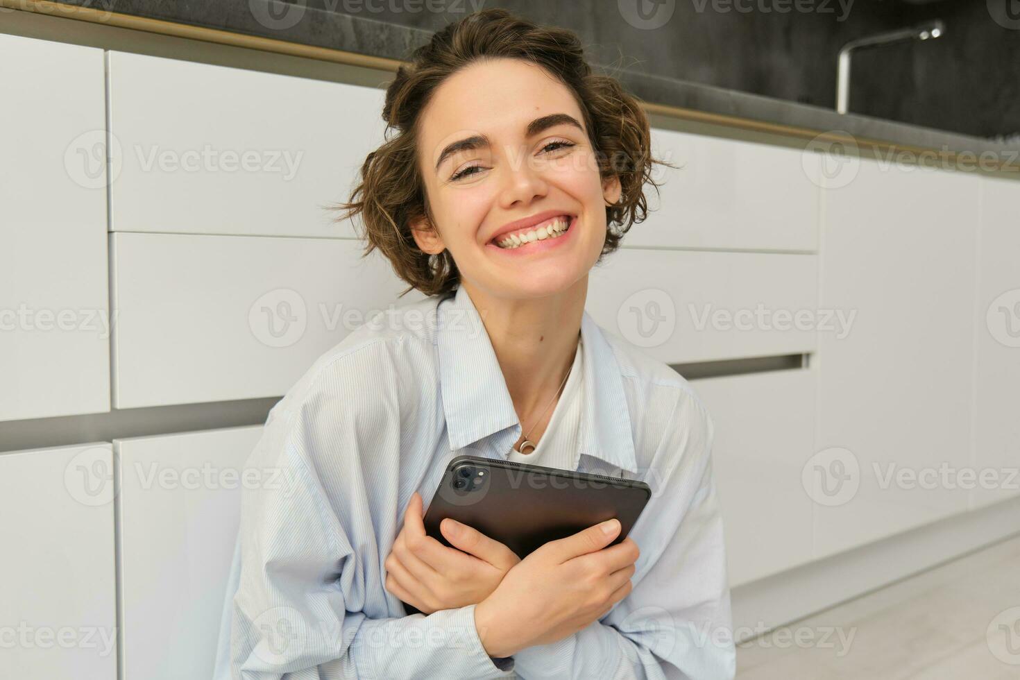 portrait de Jeune adulte femme travaux sur sa tablette, est assis avec  carnet sur cuisine sol à maison, études dans confort 35811552 Photo de  stock chez Vecteezy