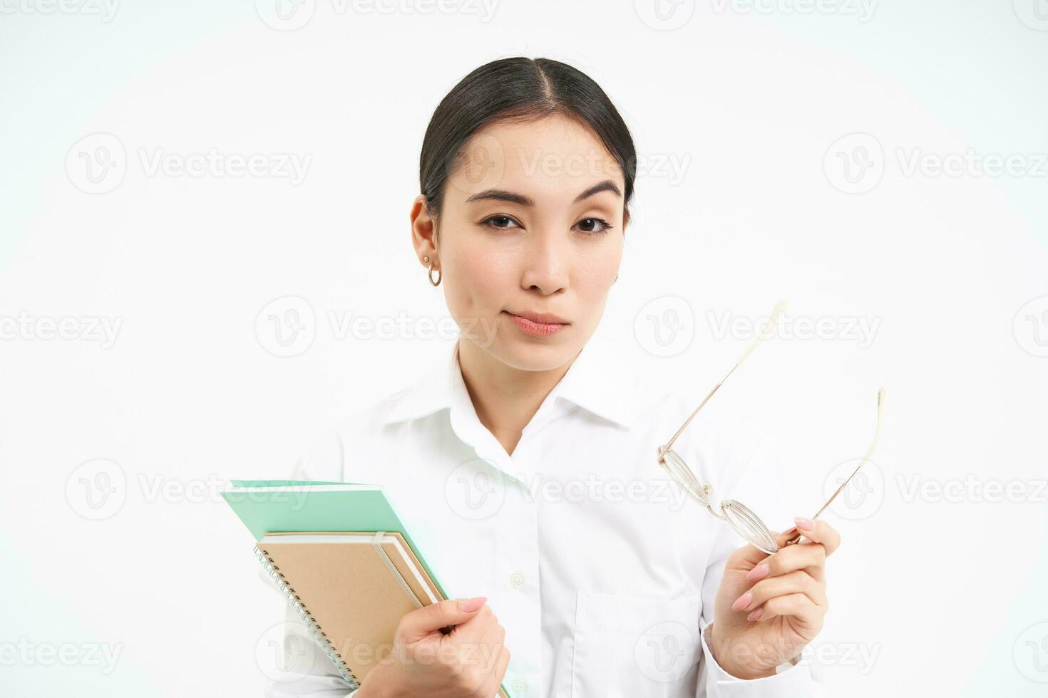 sur de soi Jeune femme, Bureau ouvrier avec lunettes, détient des cahiers, regards réfléchi, pensée, permanent isolé sur blanc Contexte photo