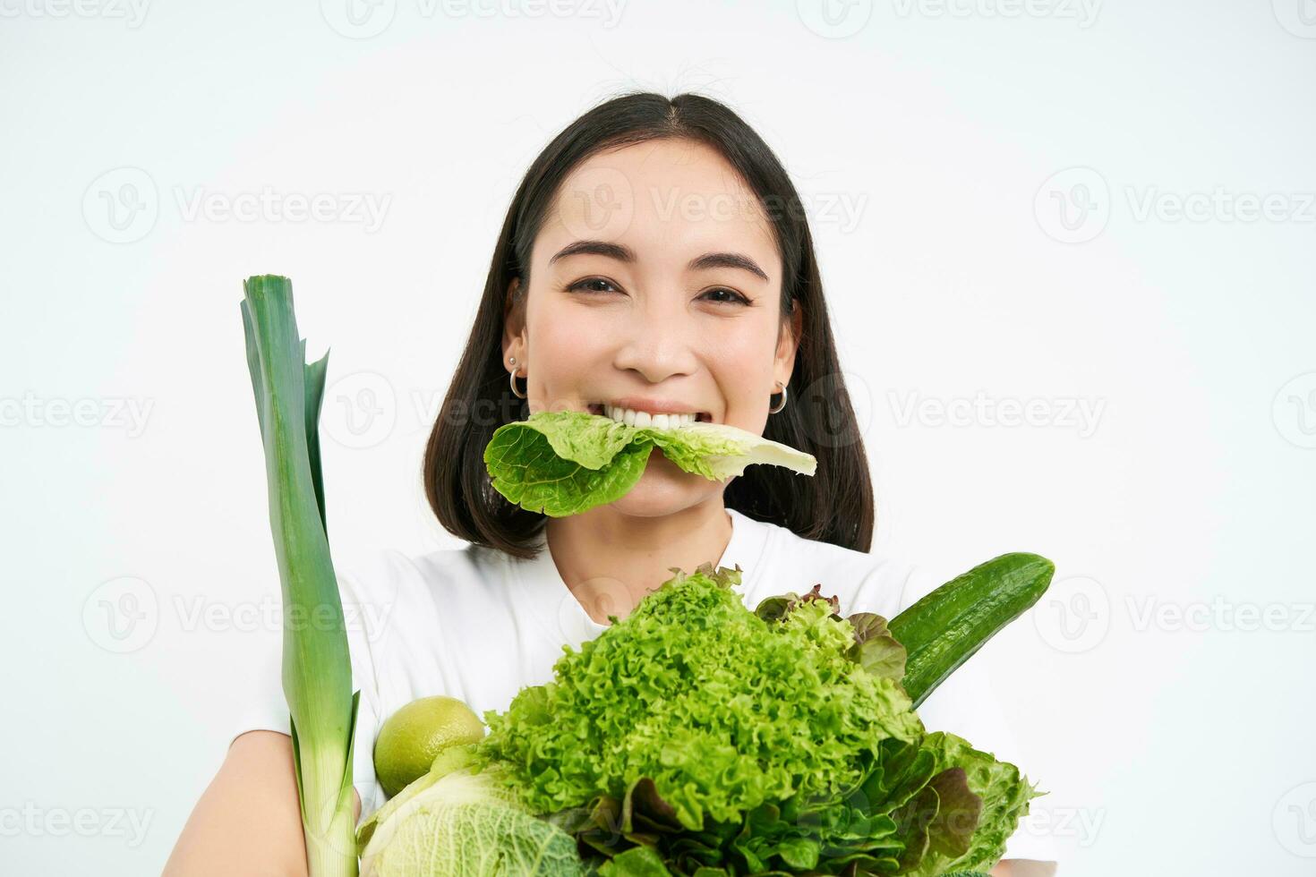 portrait de souriant coréen femme mange salade feuille, en portant vert légumes, en mangeant nutritif nourriture, blanc Contexte photo