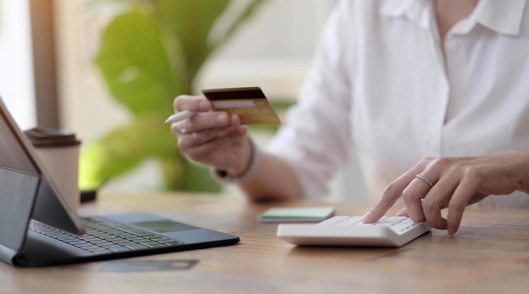 femme faisant des calculs et faisant des achats en ligne avec une carte de crédit. femme utilisant la calculatrice, le budget et le papier de prêt au bureau. factures, budget de la maison, impôts, épargne, finances, économie, audit, concept de dette photo