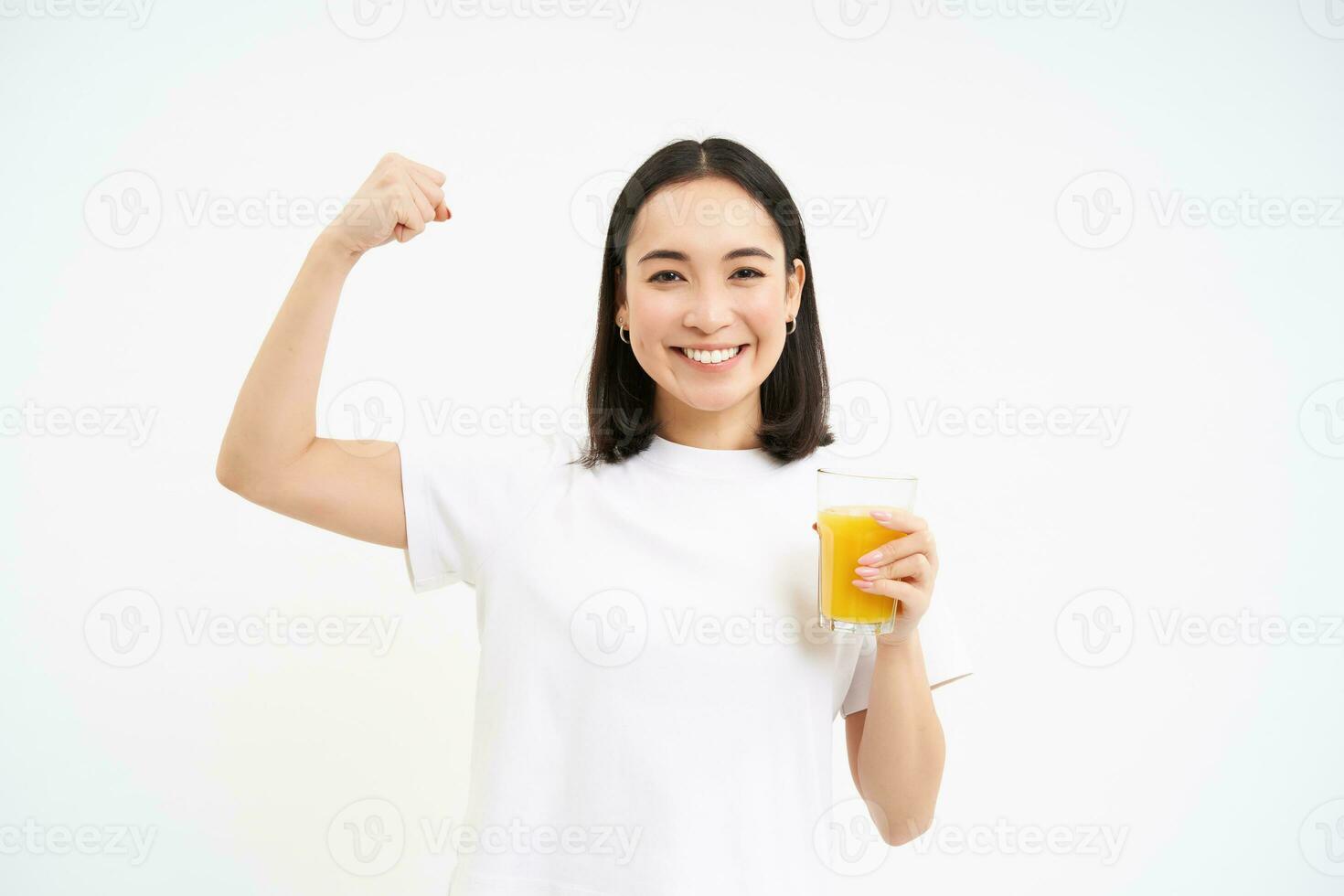 en bonne santé mode de vie. souriant Jeune asiatique femme, spectacles fort muscles, biceps sur main et les boissons Orange jus, blanc Contexte photo